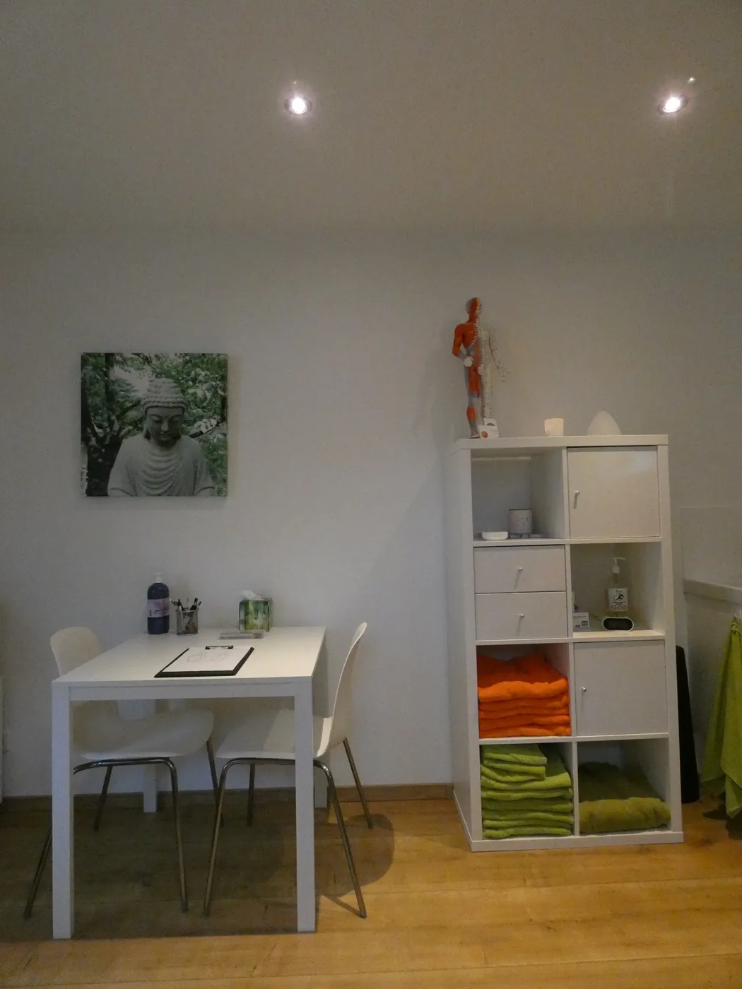 Tafel met stoelen en een kast met handdoeken in de praktijk van Erifar